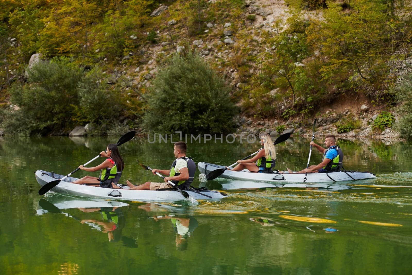 A group of friends enjoying having fun and kayaking while exploring the calm river, surrounding forest and large natural river canyons.