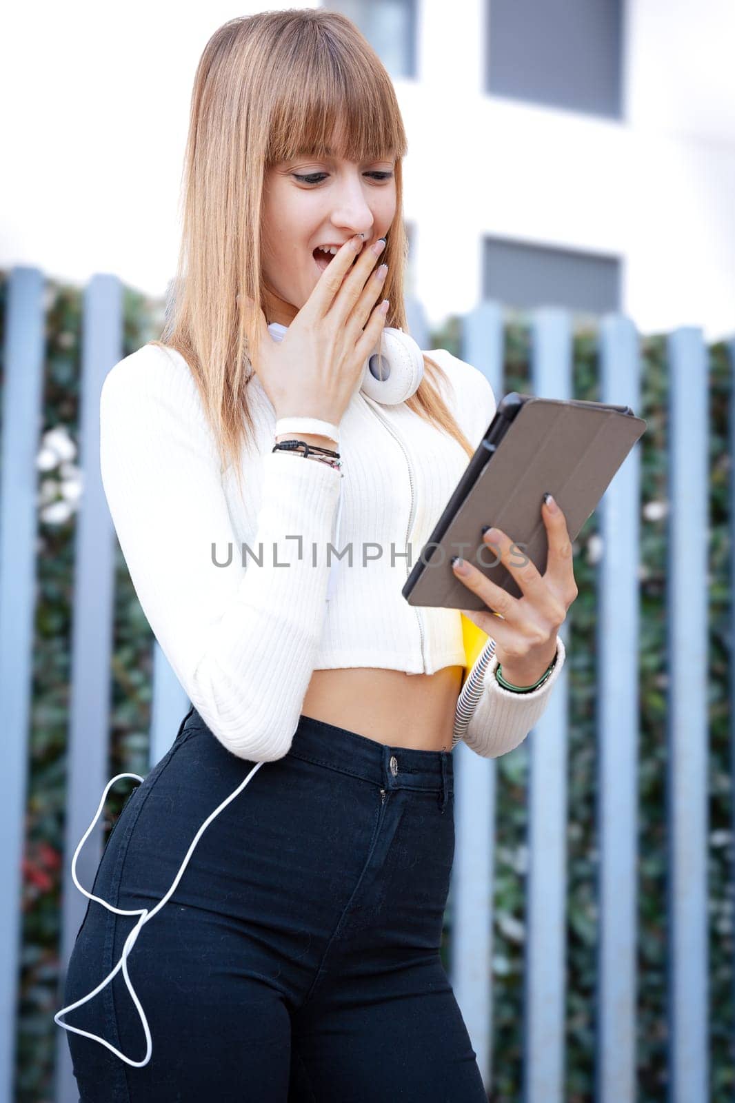 Front view of a shocked Caucasian teenager, using a social media app with her digital tablet. Concept of University Life
