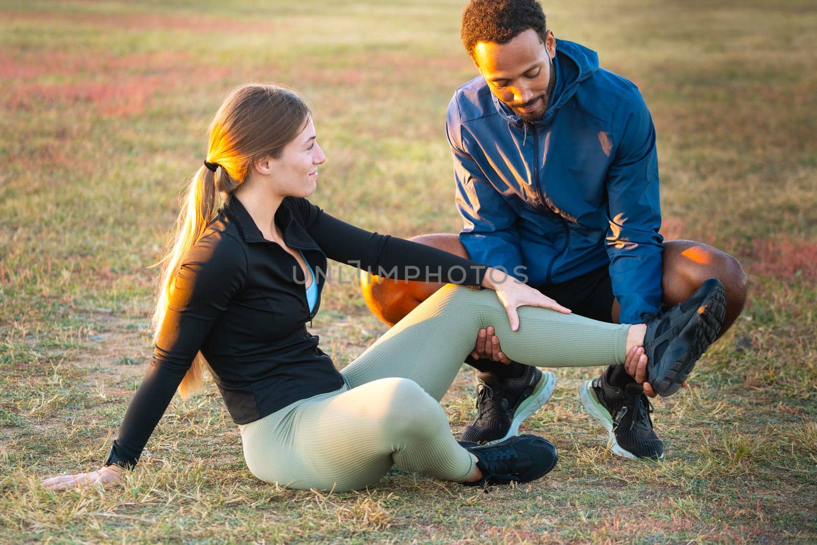 A man receives first aid after suffering an accident while running.Female athlete injured leg seen by male physiotherapist