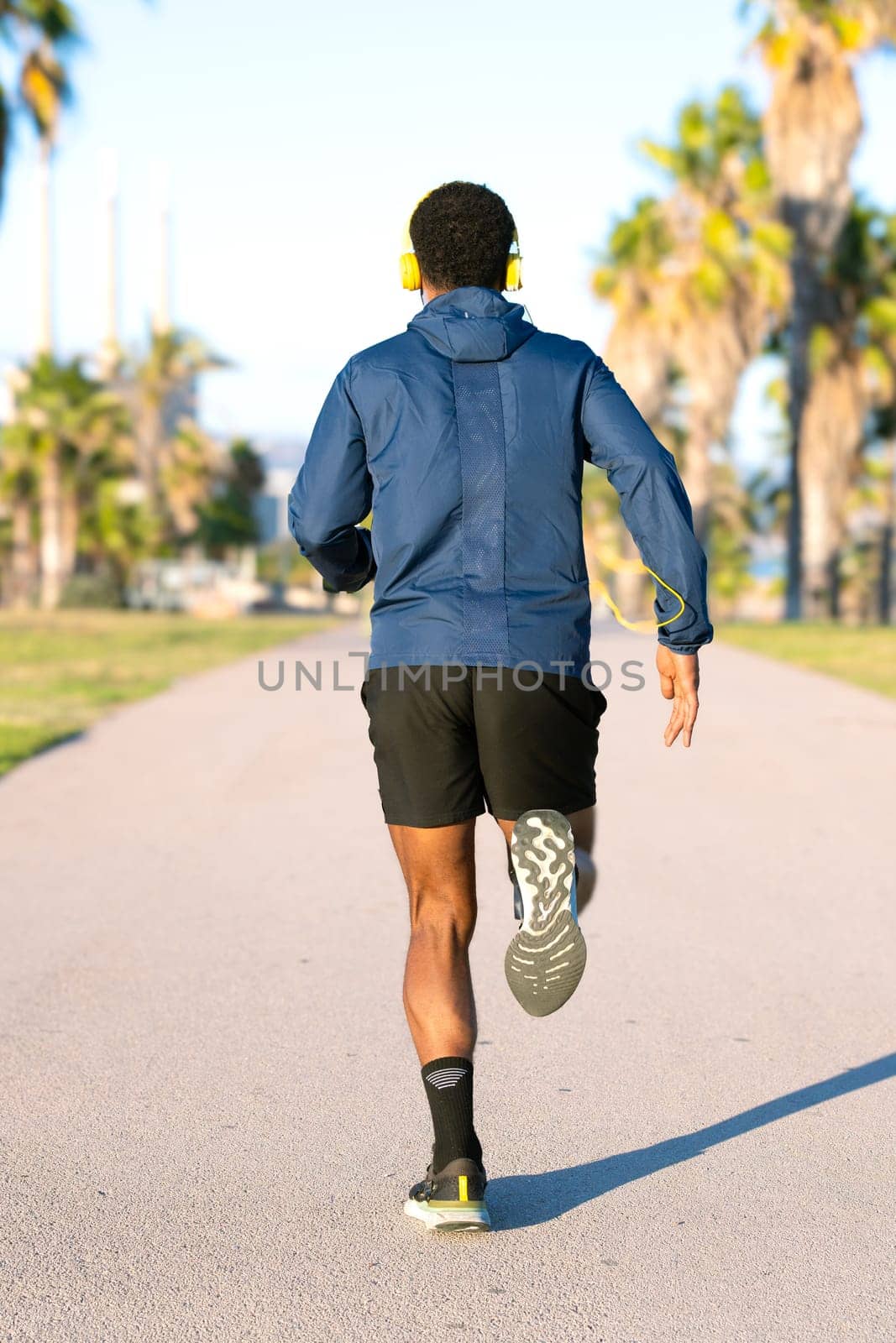 Rear view jockster running through city streets, with a bottle of water.Vertical by mariaphoto3