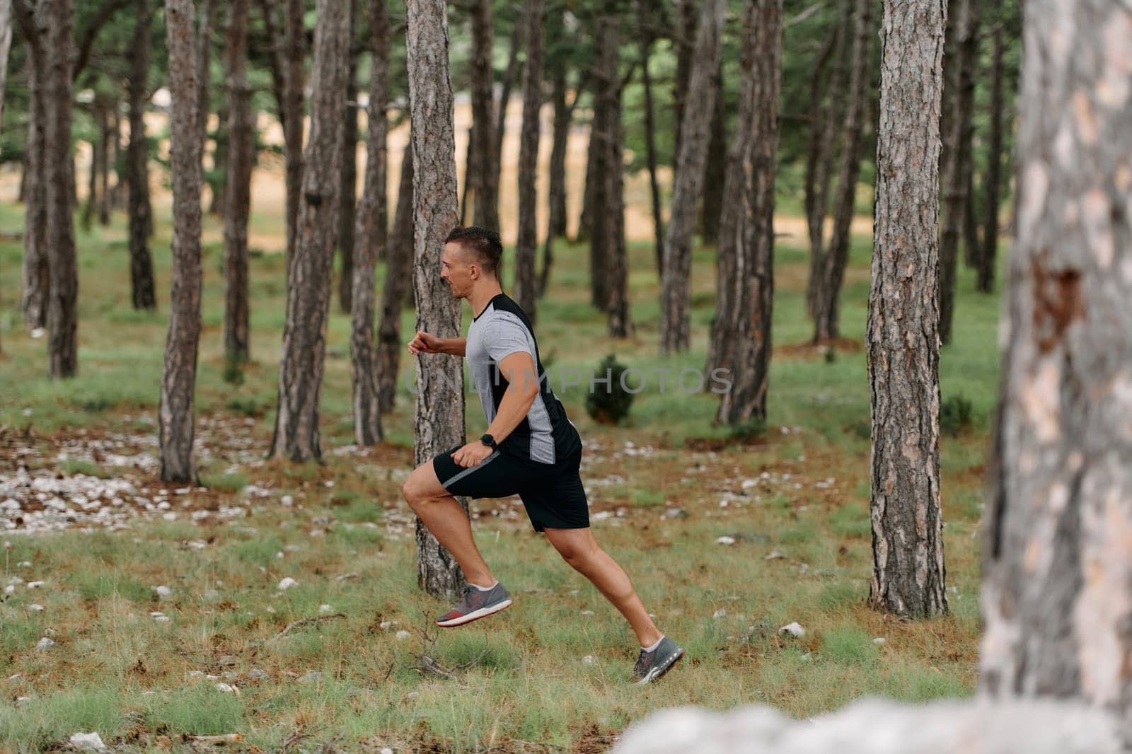 An unwavering man dashes through perilous forest paths, skillfully hurdling over wooden obstacles with determination and agility, epitomizing courage and athleticism