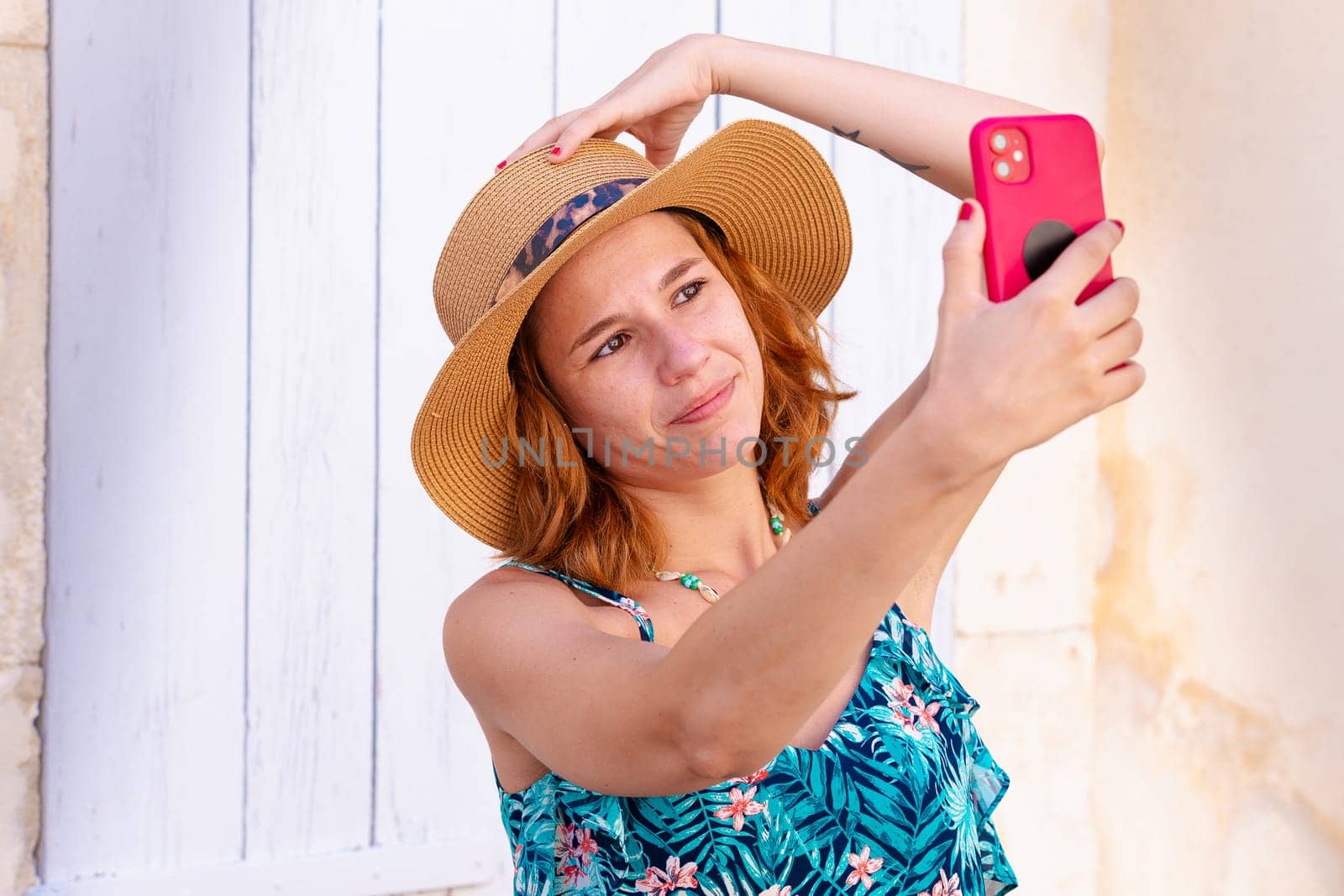 Beautiful Caucasian woman in hat smiling taking a selfie outdoors. by molesjuny