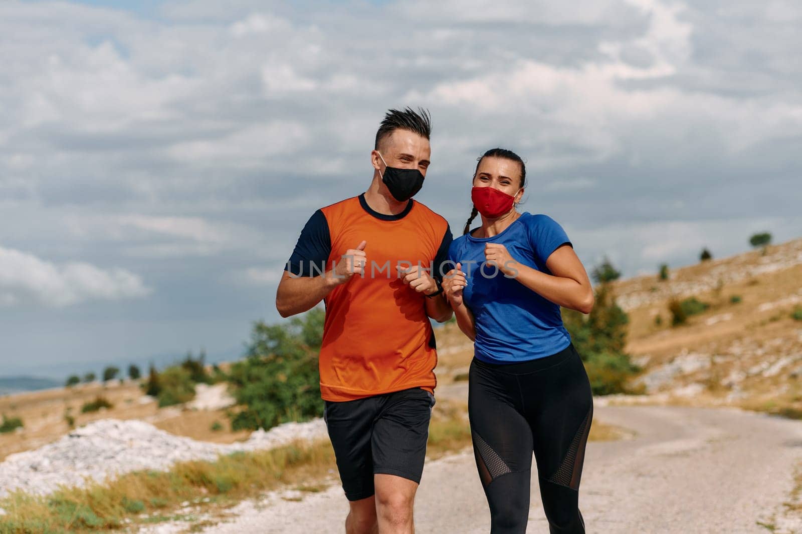 Couple running in nature at morning wearing protective face masks.