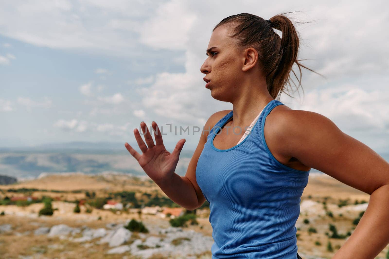 A determined female athlete runs through a forest trail at sunrise, surrounded by breathtaking natural beauty and vibrant greenery.