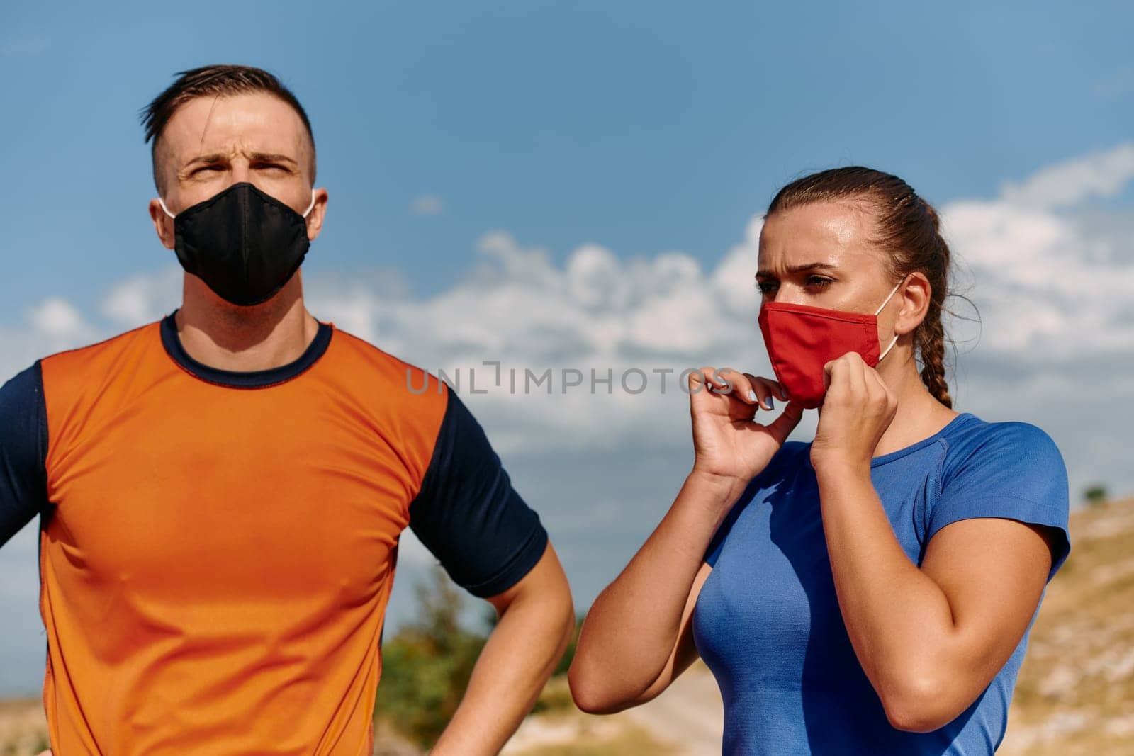 Couple running in nature at morning wearing protective face masks.