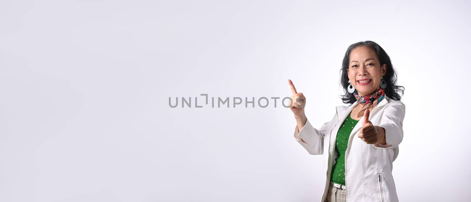 Smiling senior businesswoman pointing aside with copy space isolated on white background.