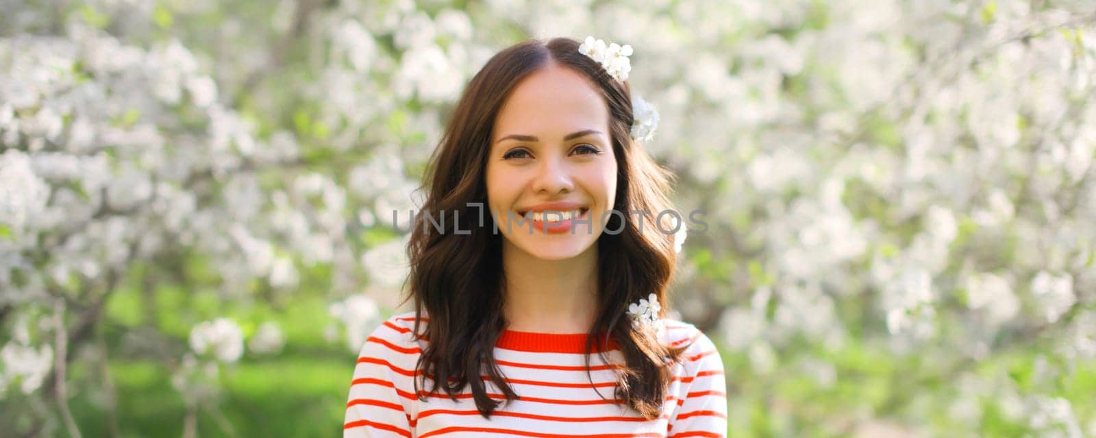 Lovely happy smiling young woman in spring blooming garden with white flowers on the trees in park by Rohappy