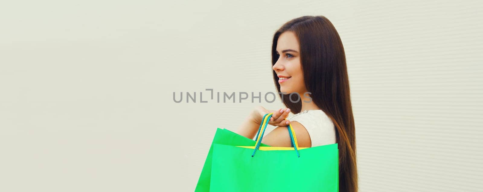 Portrait of beautiful brunette happy smiling young woman posing with colorful shopping bags on white background