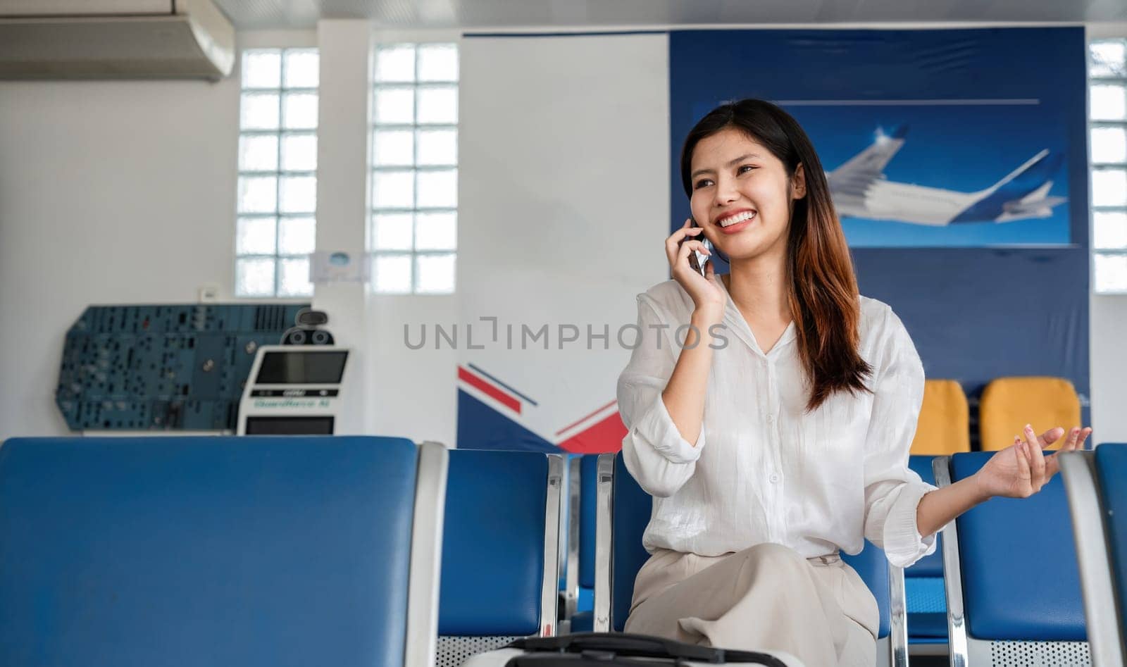 Young woman talking on smartphone at airport. Concept of travel and communication.