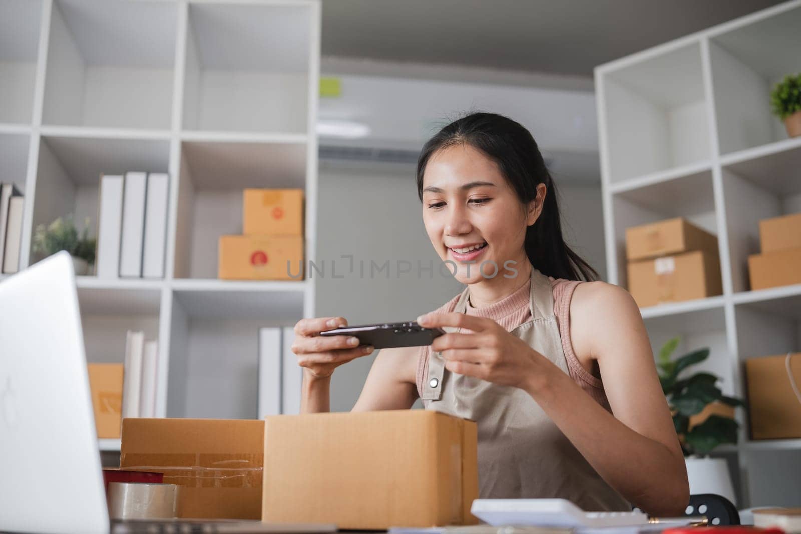 Businesswoman taking photos of products for online store in office. Concept of e-commerce and product photography by wichayada
