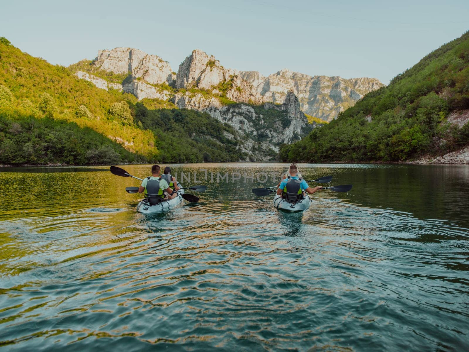 A group of friends enjoying having fun and kayaking while exploring the calm river, surrounding forest and large natural river canyons.