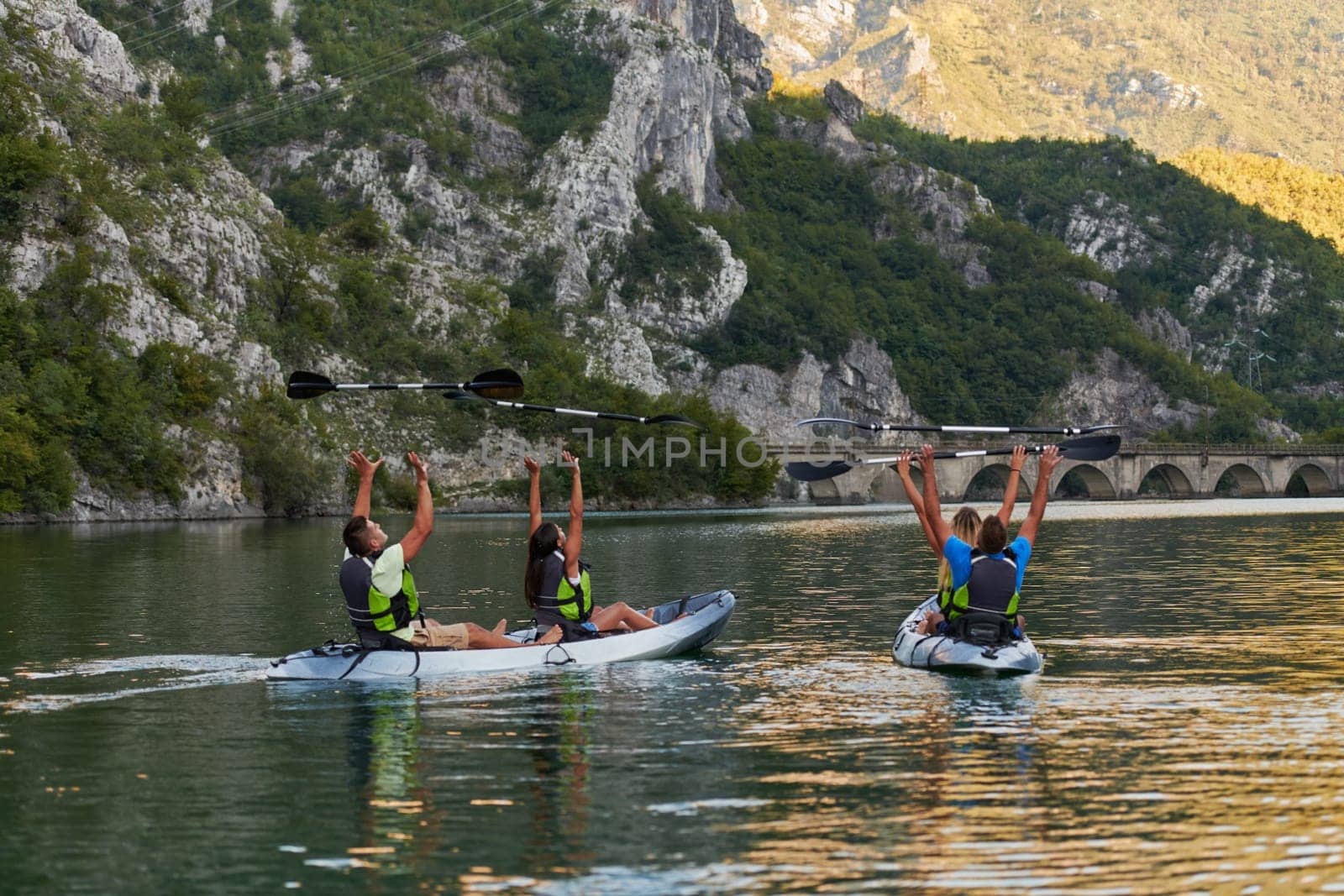 A group of friends enjoying having fun and kayaking while exploring the calm river, surrounding forest and large natural river canyons.