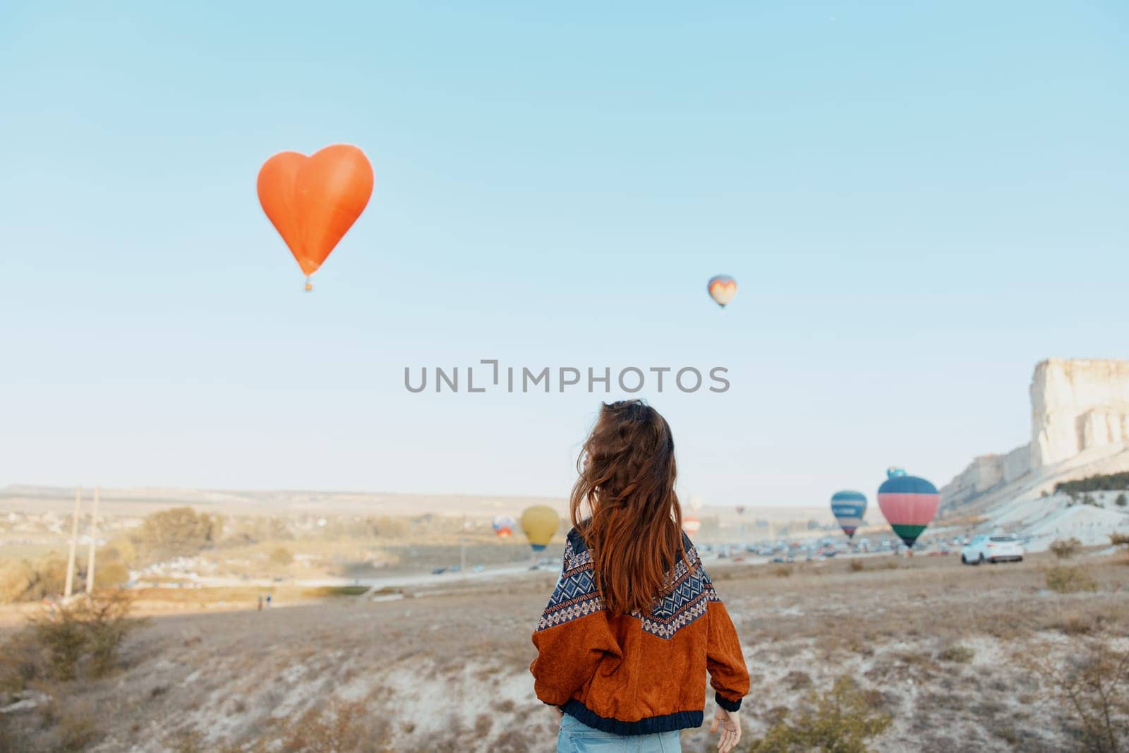Stunning view of woman admiring colorful hot air balloons floating over the unique landscape of cappadocia, turkey