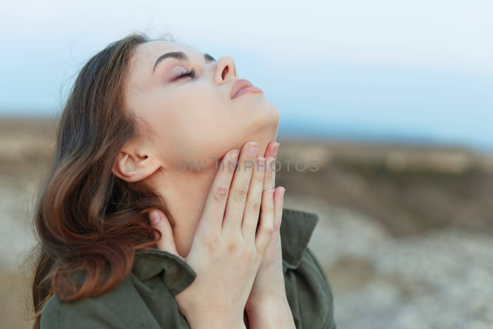 Gorgeous female model gracefully poses on the ground, touching her neck with hands in elegant fashion