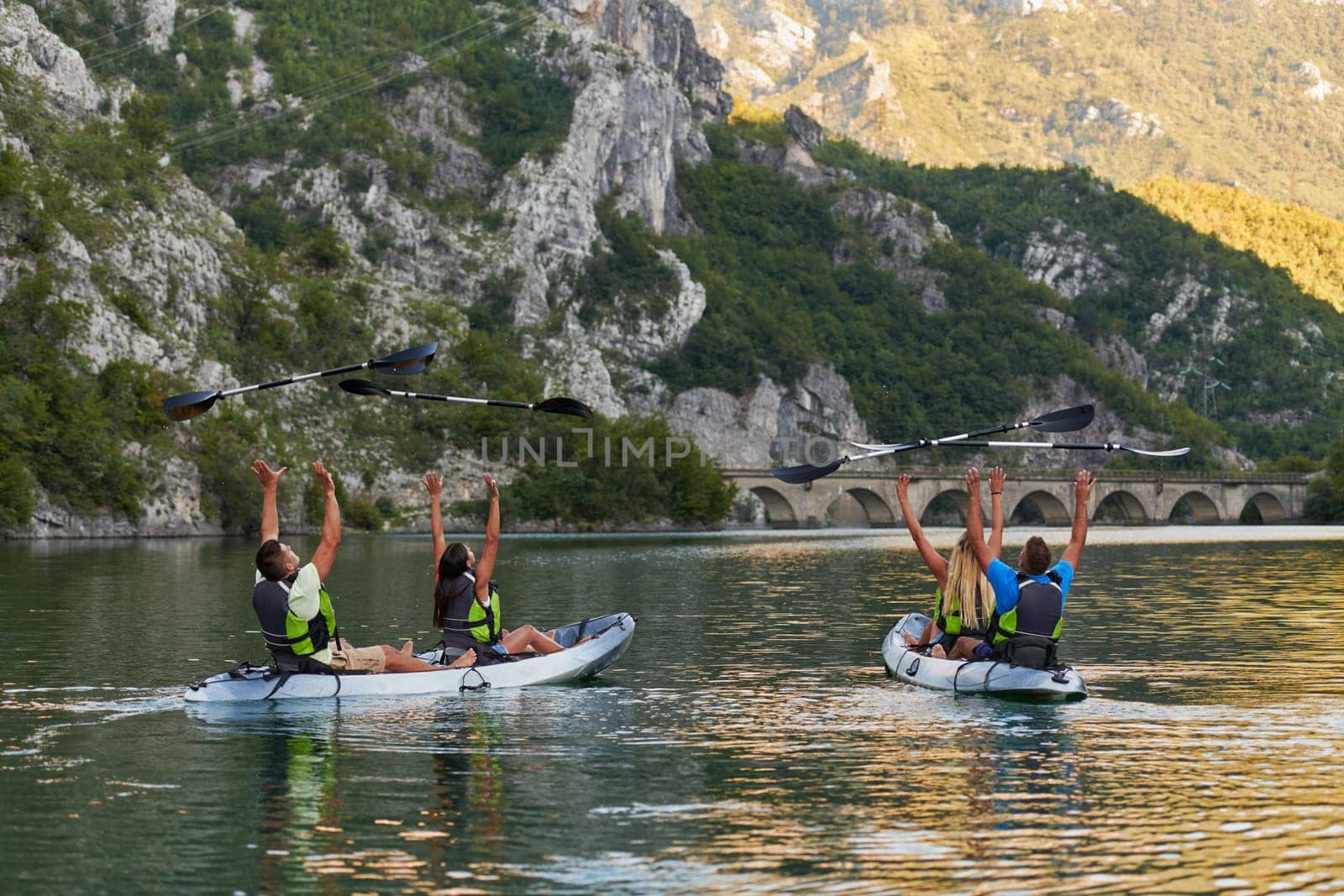 A group of friends enjoying having fun and kayaking while exploring the calm river, surrounding forest and large natural river canyons.