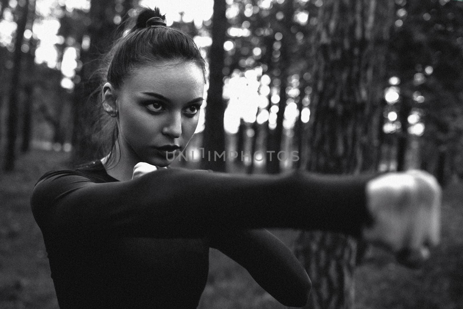 Black and white photo of a woman practicing martial arts in nature. film grain by Nickstock