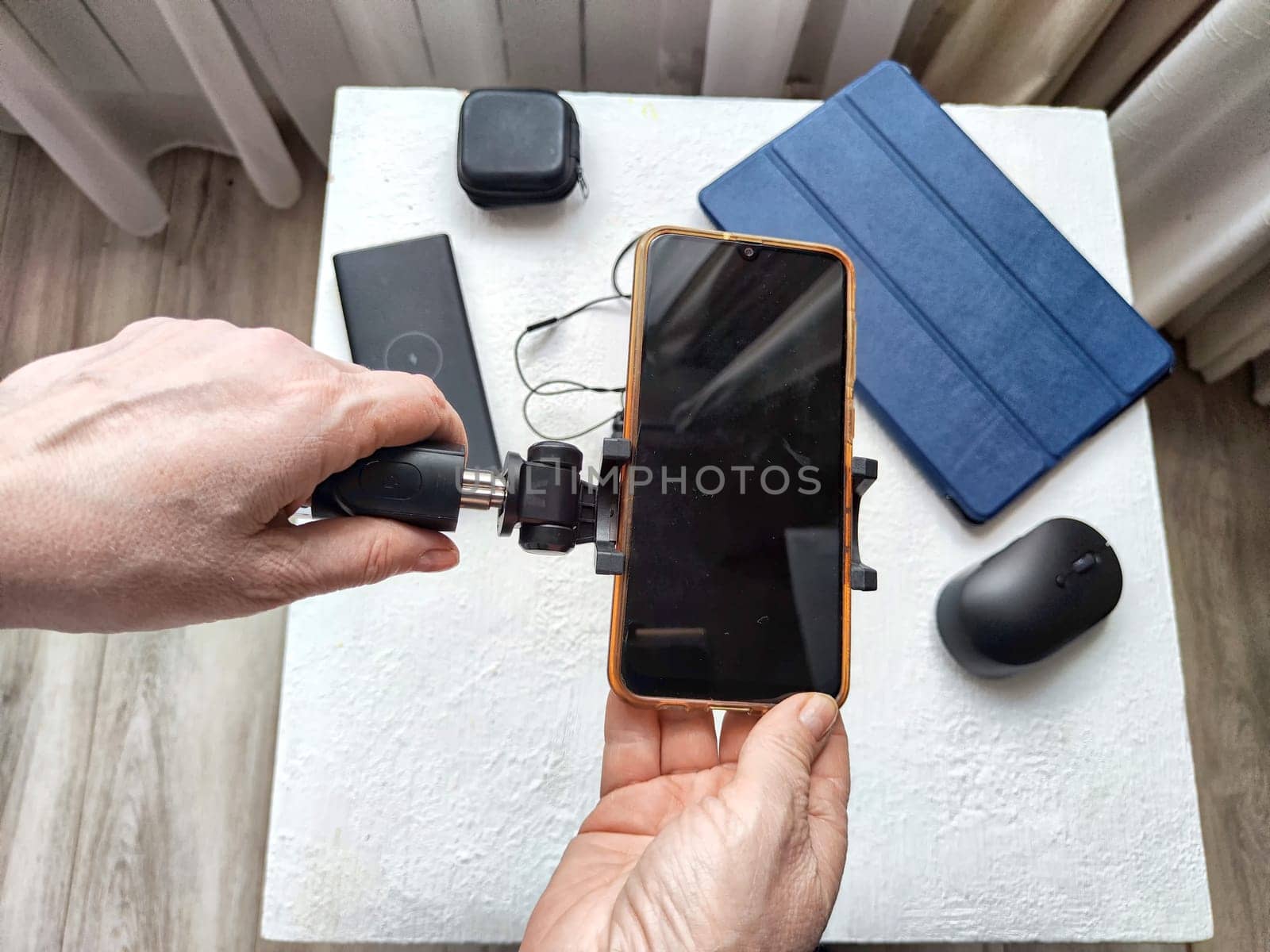 A set of useful blogger devices and hand of female blogger. A neatly organized desk featuring a smartphone, earphones, and various tech gadgets