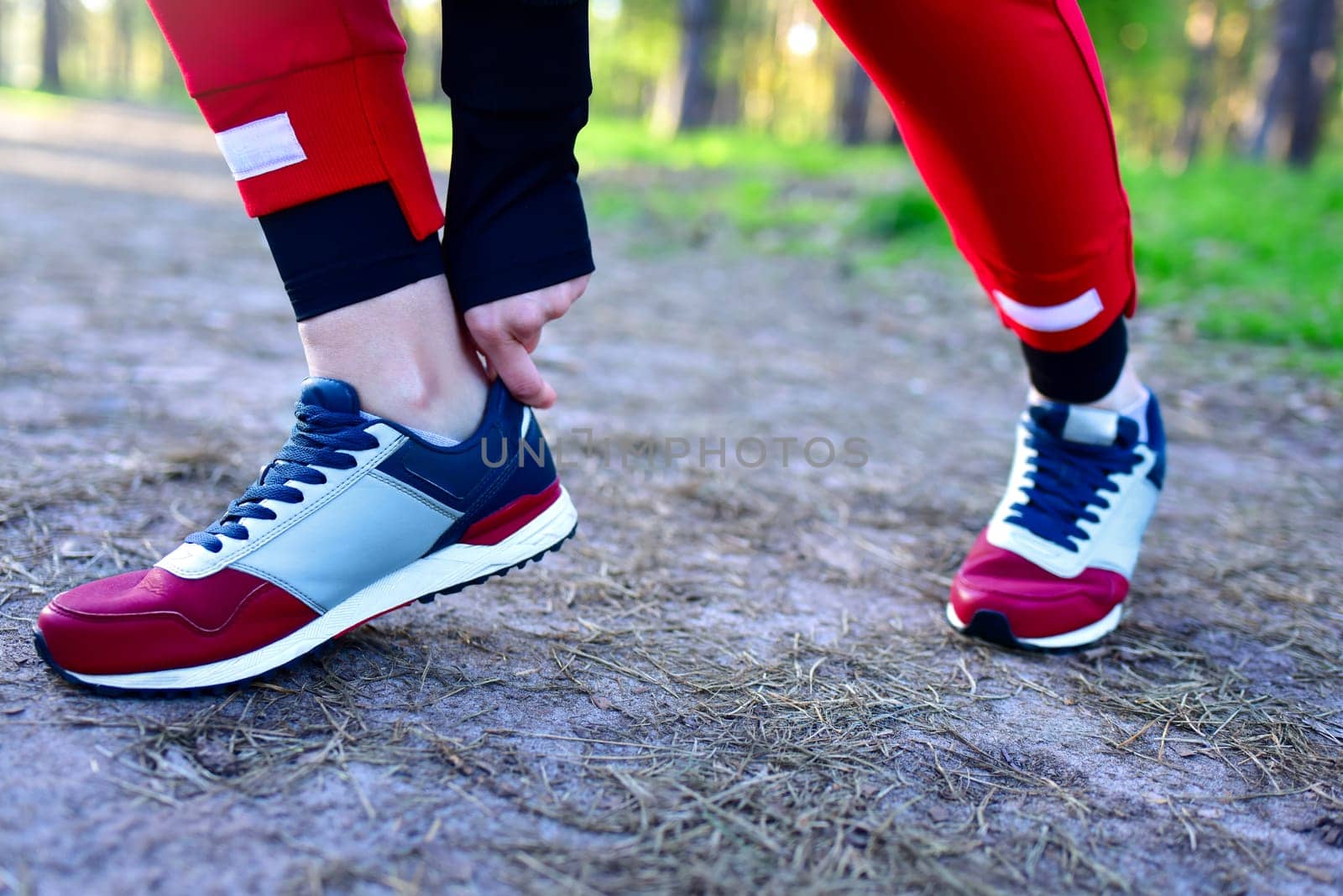 A woman on a jog in the park corrects the sneakers on her feet.