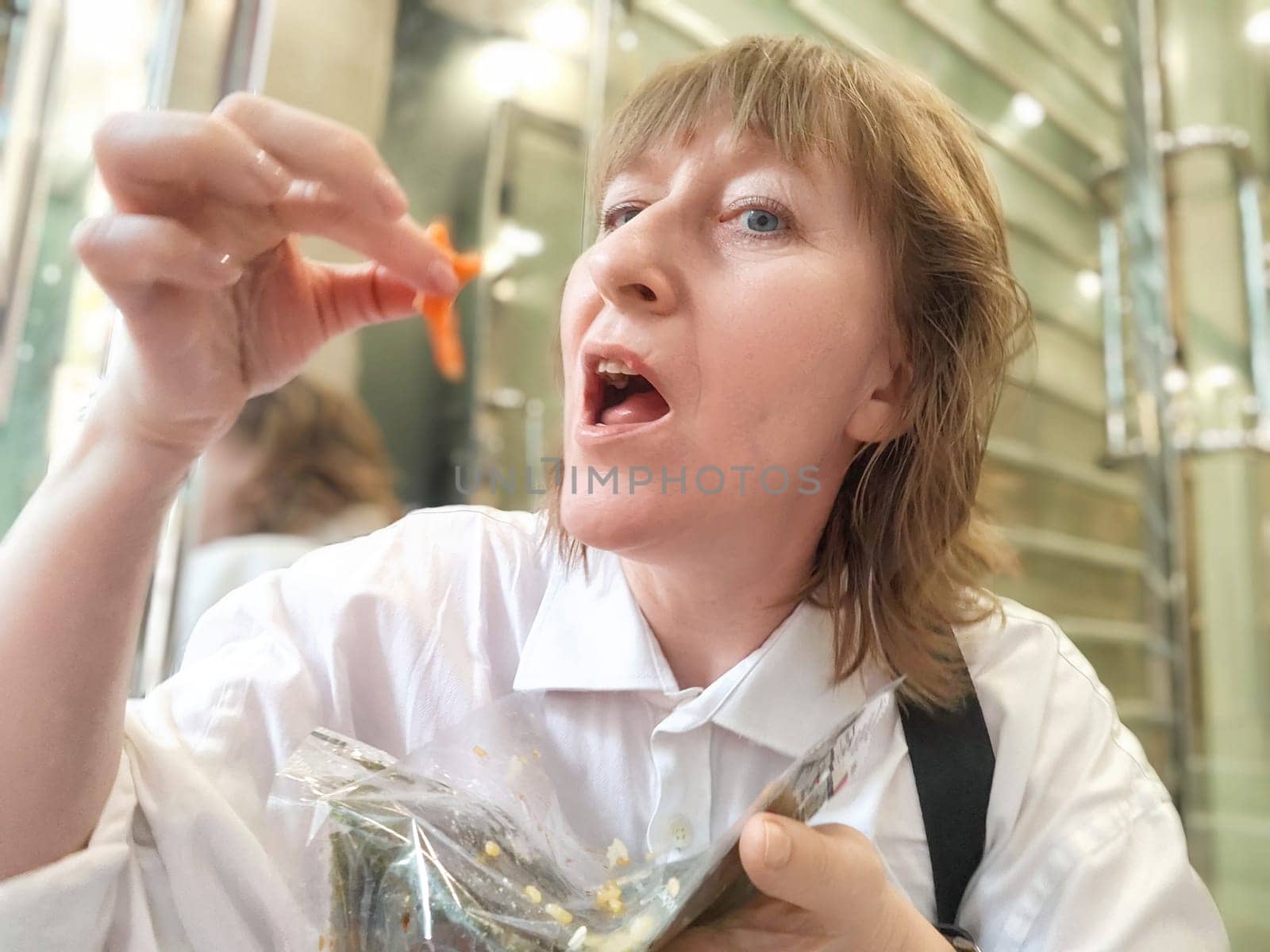 Middle-Aged Woman Enjoying Street Food on a Travel Journey in an Urban Setting, Daytime