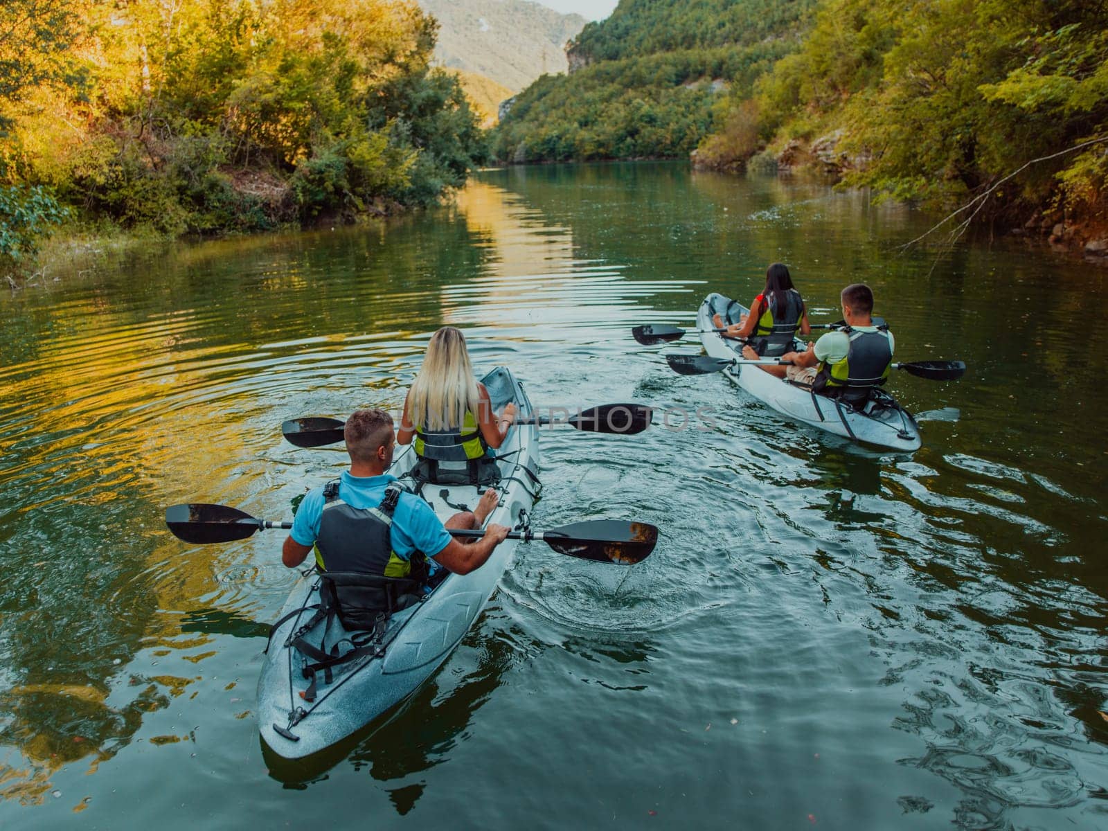 A group of friends enjoying having fun and kayaking while exploring the calm river, surrounding forest and large natural river canyons.