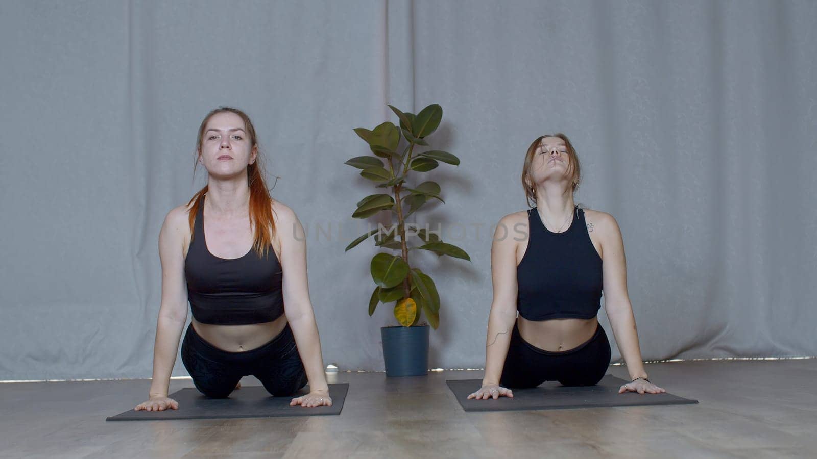 Athletic young women doing exercisizes for the spine stretching. Media. Concept of inner peace and no stress. by Mediawhalestock