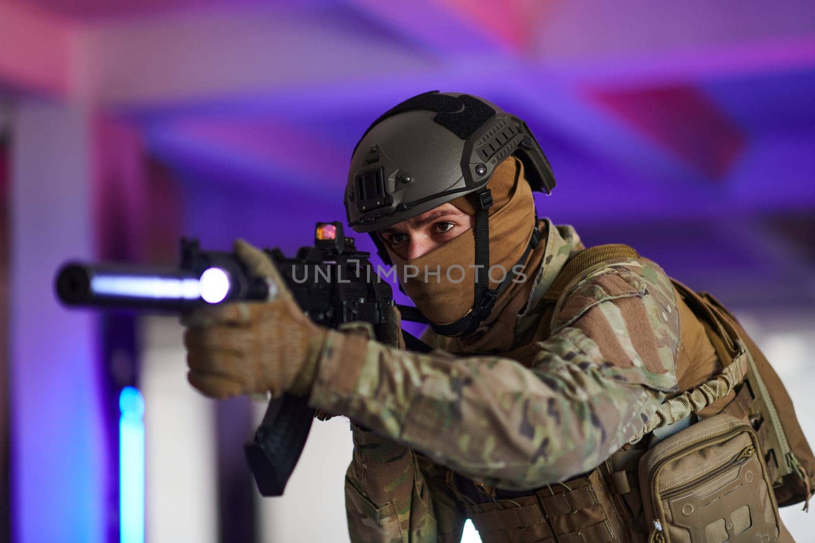 A professional soldier undertakes a perilous mission in an abandoned building illuminated by neon blue and purple lights.