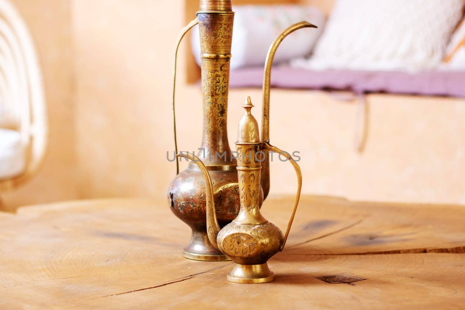 Two brass vases are elegantly placed on a rustic wooden table, creating a charming and stylish decor piece