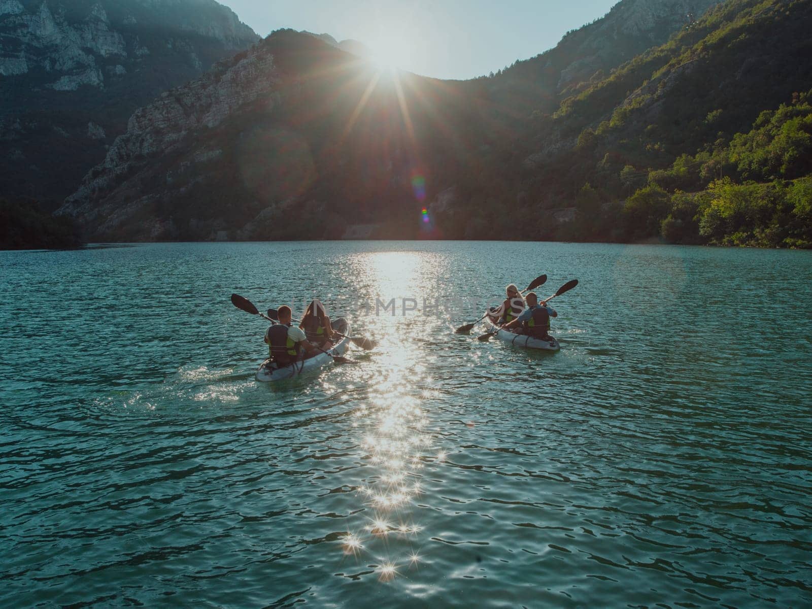 A group of friends enjoying fun and kayaking exploring the calm river, surrounding forest and large natural river canyons during an idyllic sunset