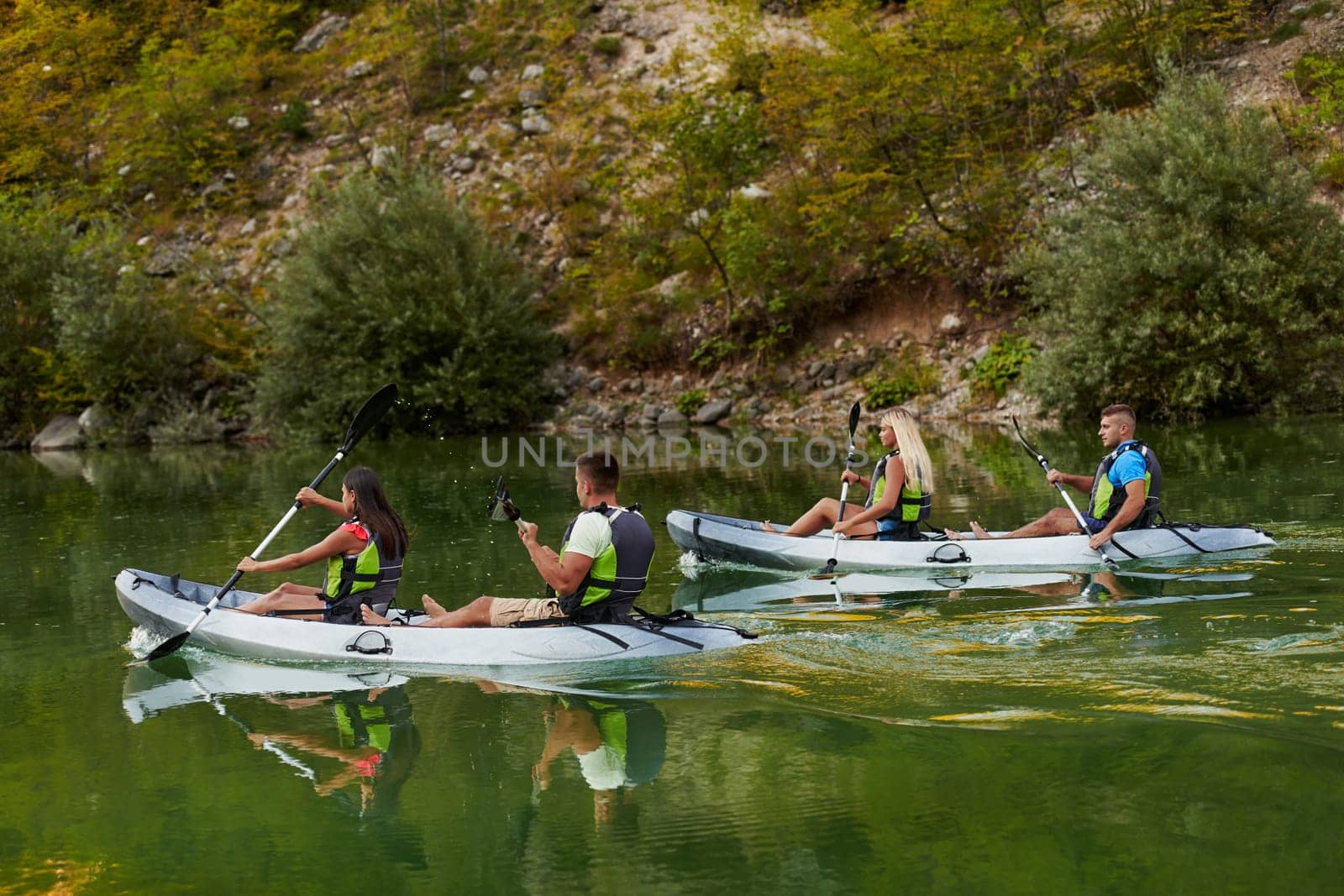 A group of friends enjoying having fun and kayaking while exploring the calm river, surrounding forest and large natural river canyons.