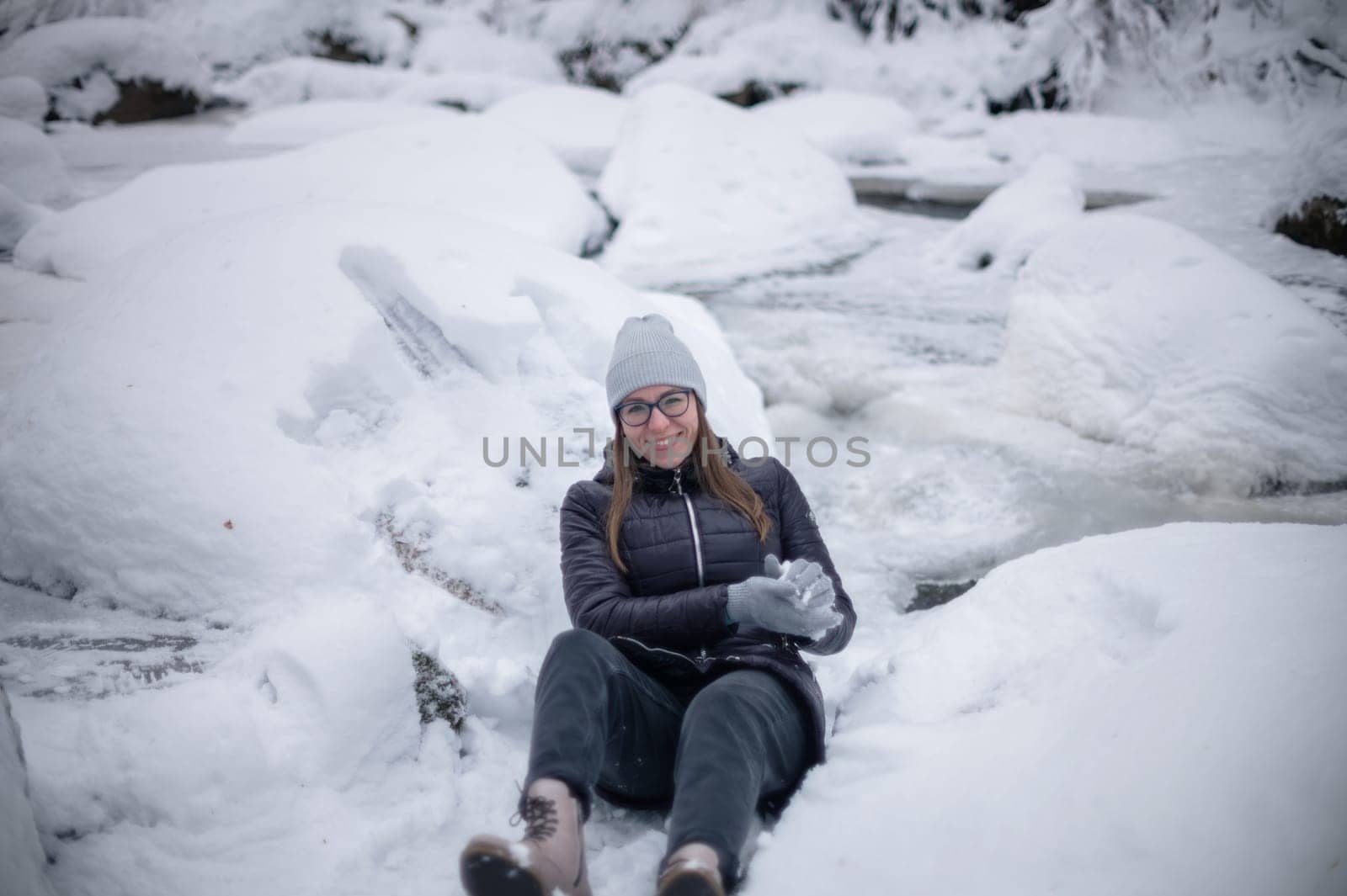 Woman in winter jacket walking in snowy winter forest, snowy winter day