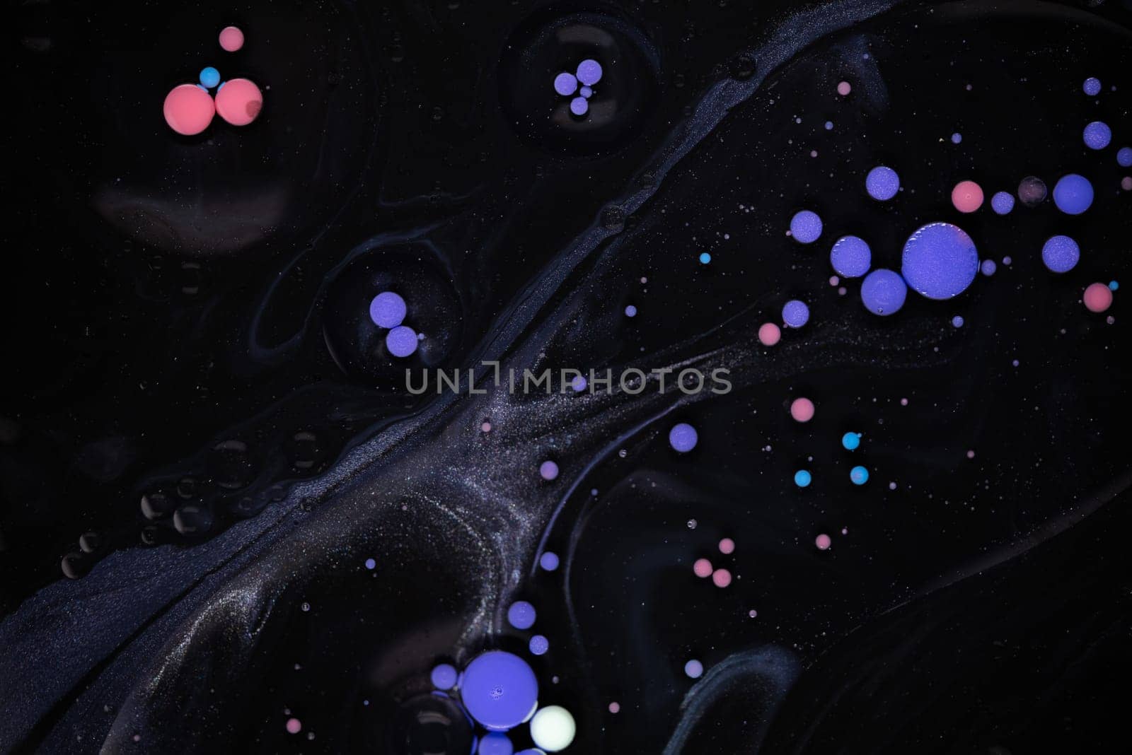 A myriad of oil droplets intermingling with water, creating a mesmerizing effect reminiscent of a galaxy.