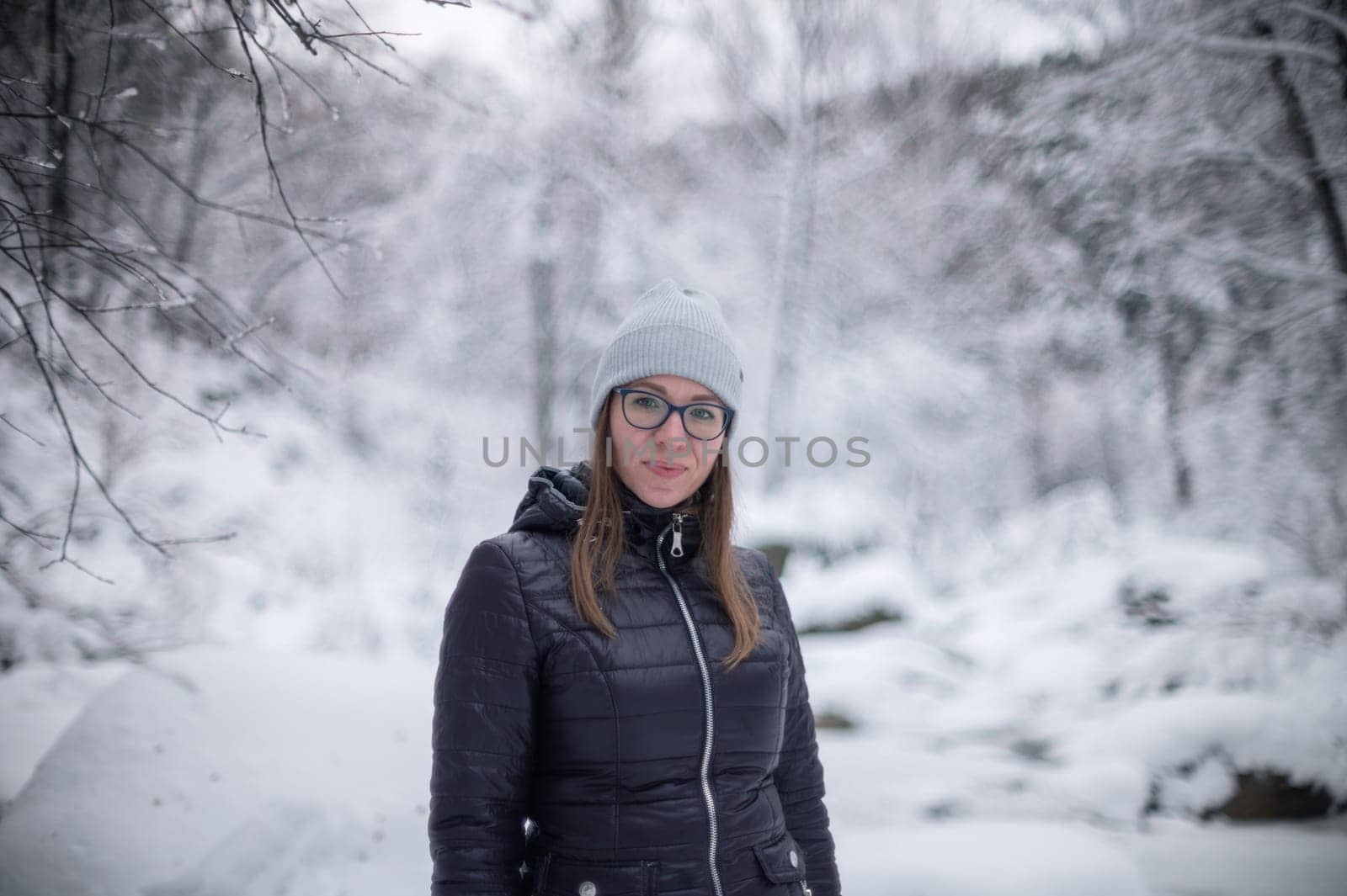 Woman in winter jacket walking in snowy winter forest, snowy winter day