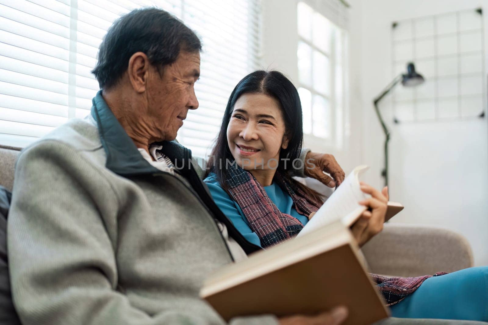 senior married couple enjoying quality time reading books together on the couch.