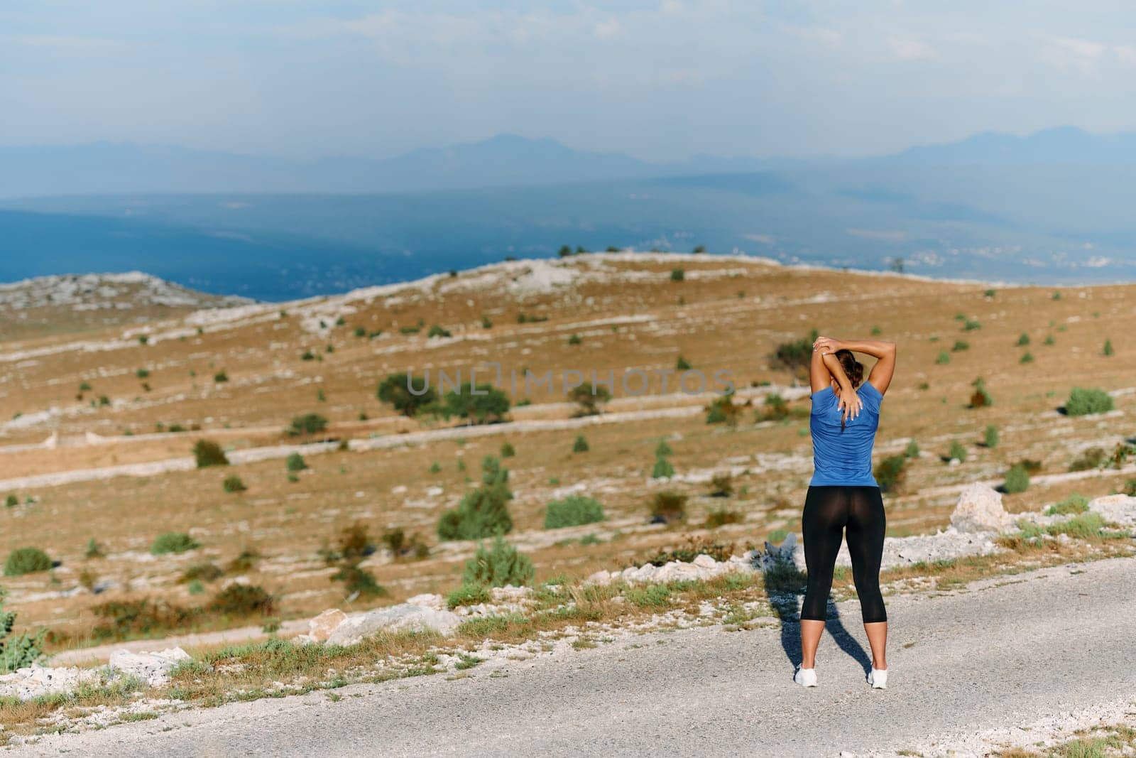 Determined Female Athlete Stretching After an Intense Run Through Rugged Mountain Terrain. by dotshock