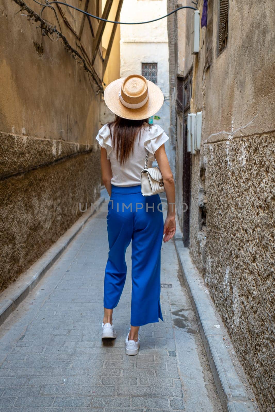 Young Woman in Hat Walking Through the Streets of Fez, Morocco