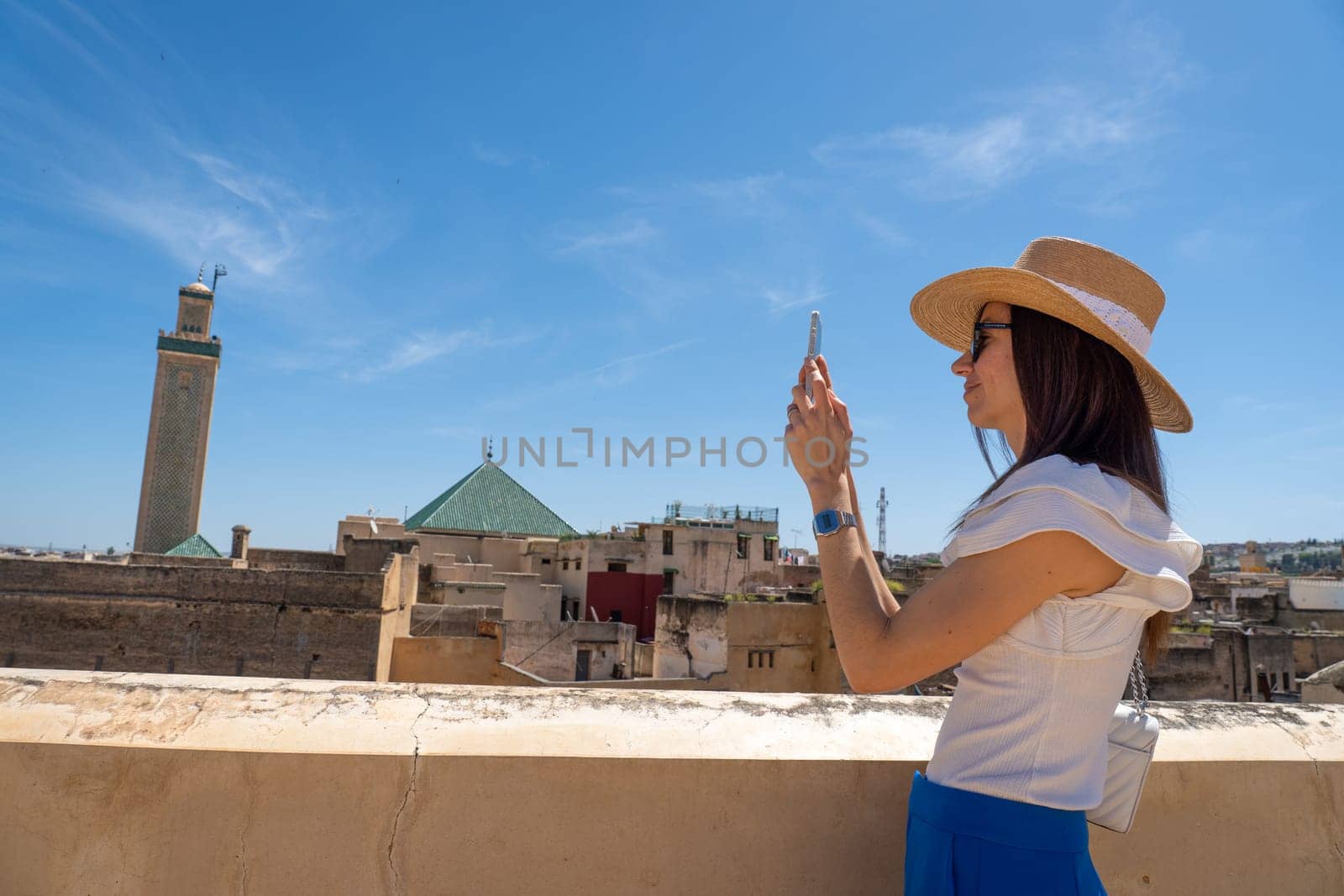 Young Woman in Hat Photographing Fez Cityscape with Smartphone, Morocco