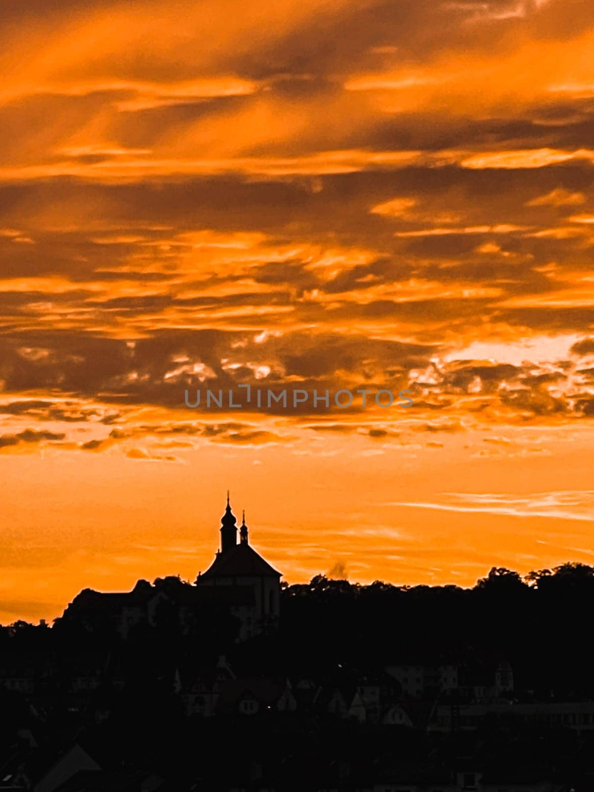 simple background of city silhouette shape of buildings roofs antennas and high voltage objects, vibrant orange sky view . High quality photo