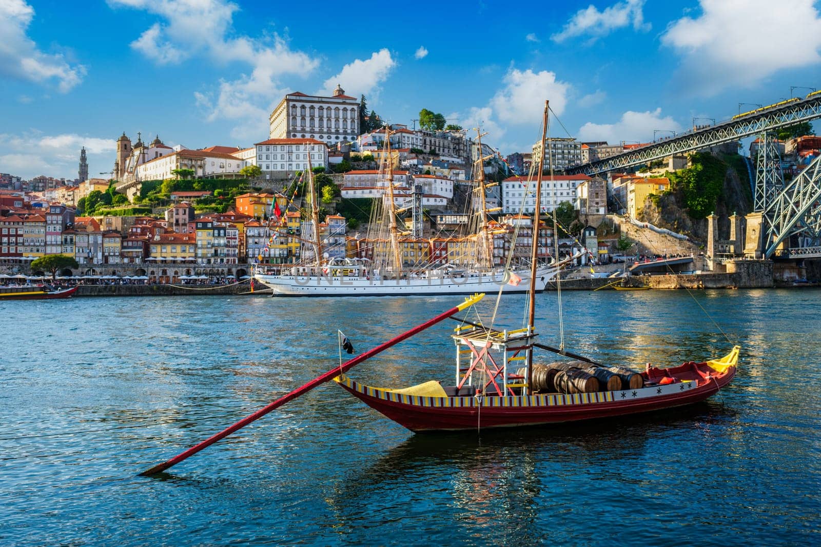 View of Porto city and Douro river with traditional boats with port wine barrels and sailing ship from famous tourist viewpoint Marginal de Gaia riverfront. Porto, Vila Nova de Gaia, Portugal