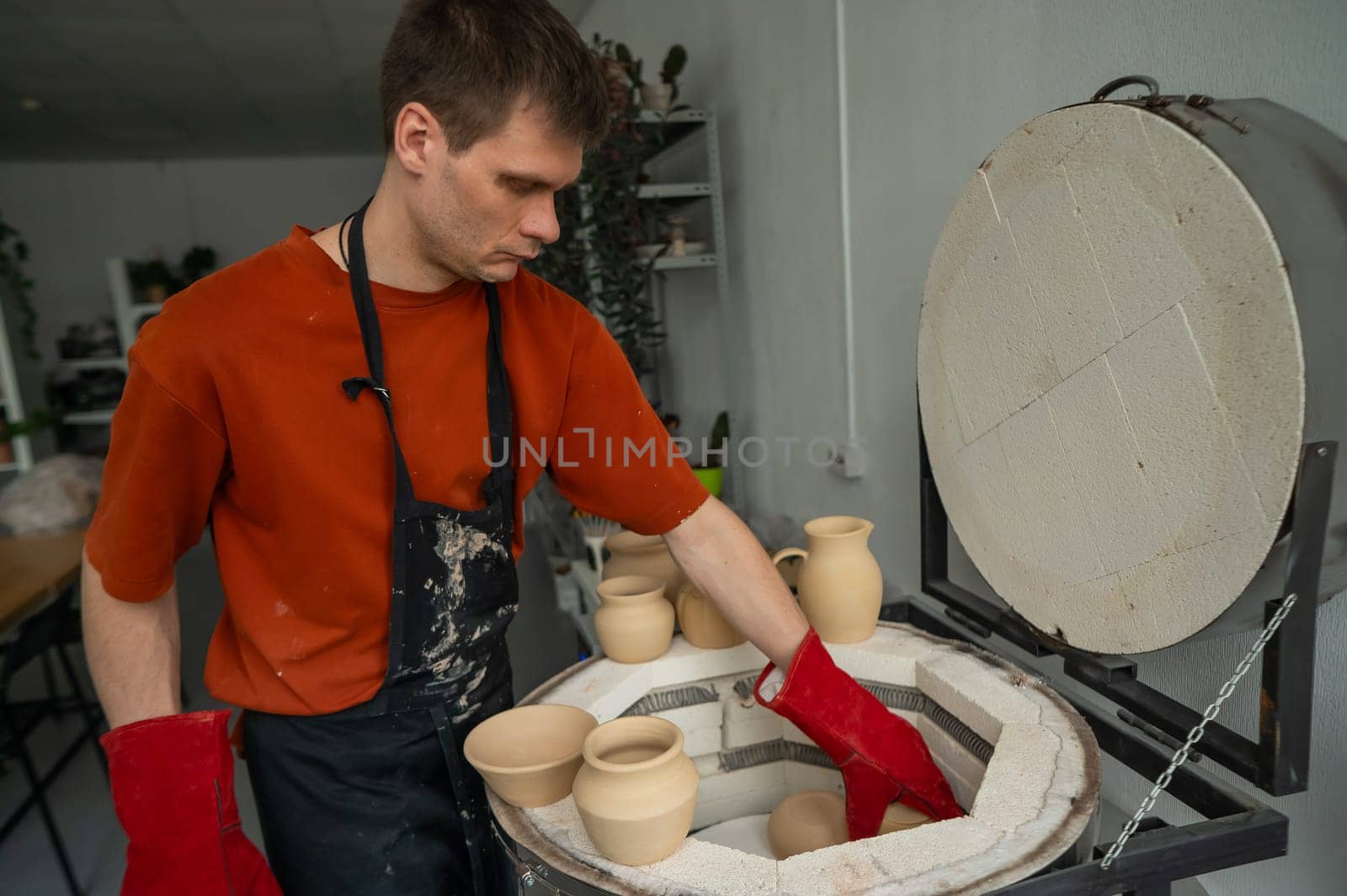 Caucasian man loading ceramic products into a special kiln. by mrwed54