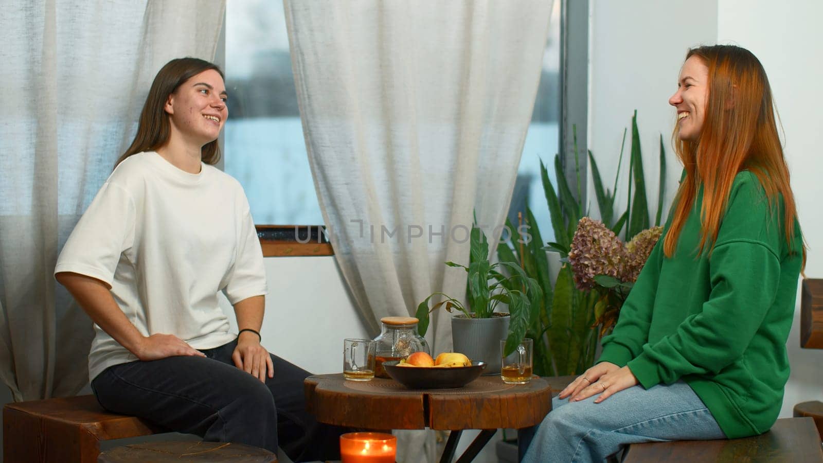 Young women drink tea and have fun chatting in cafe. Media. Young students are having fun talking in cozy college cafe. Women drink tea and laugh in cafe by Mediawhalestock