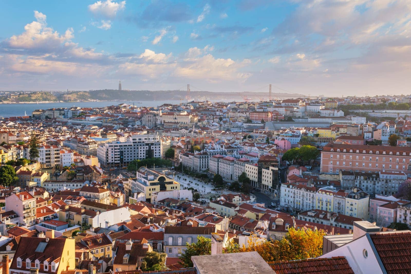 View of Lisbon famous view from Miradouro da Senhora do Monte tourist viewpoint of Alfama and Mauraria old city districts, 25th of April Bridge on sunset. Lisbon, Portugal