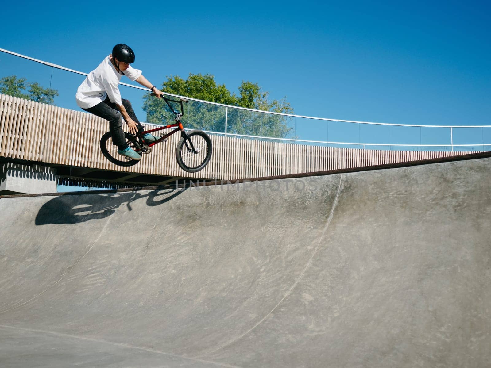 BMX rider performing aerial trick Toboggan on concrete quarter pipe in skatepark. Skilled BMX freestyler jumping over quarter pipe ramp skatepark. Young BMX bicycle rider having fun and posing. Copy space