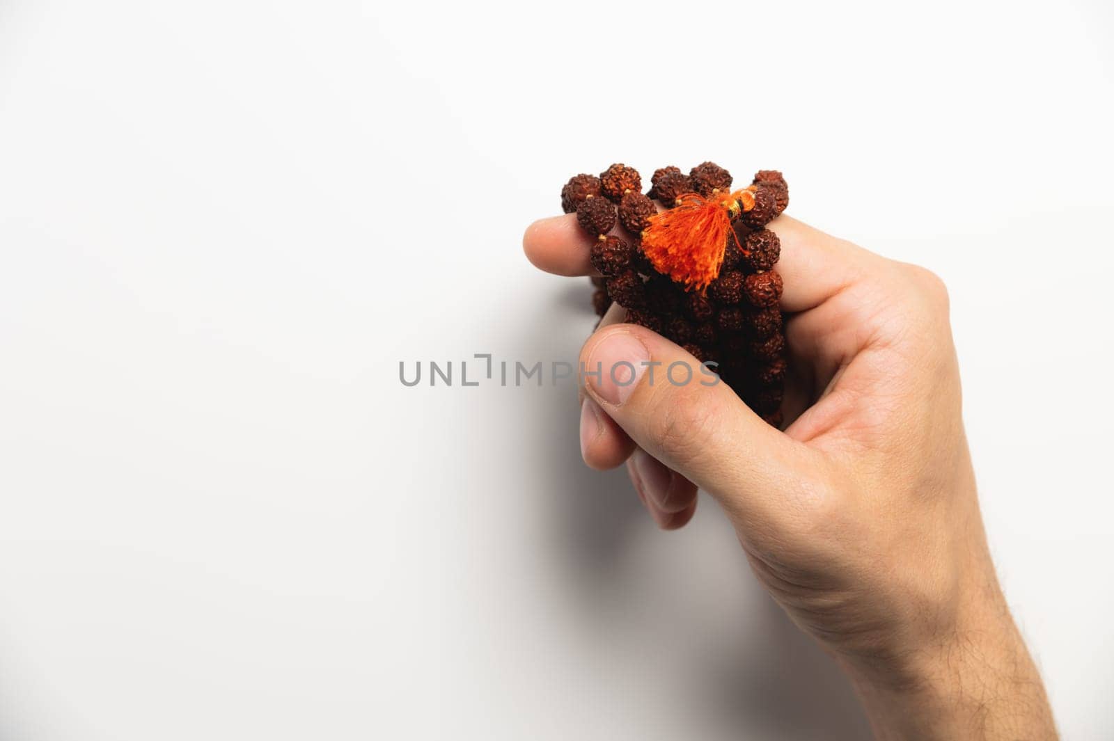 Selective focus, man's hands holding wooden rosary beads on white background.