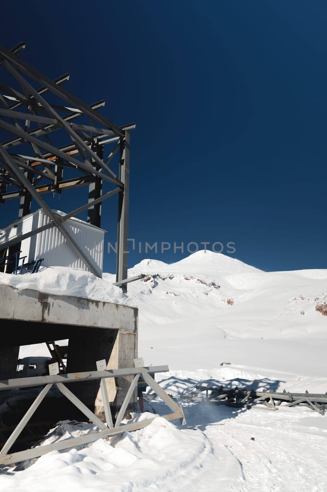 A cable car station high in the mountains under construction. Snowy mountain landscape and construction of a metal structure for a cable car.