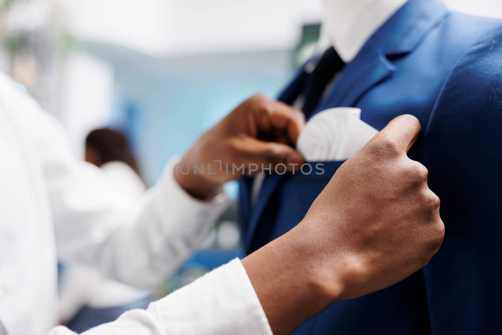 African american man hands checking formal jacket fit on mannequin in clothing store. Shopping mall assistant arms adjusting suit on dummy model, displaying apparel new collection