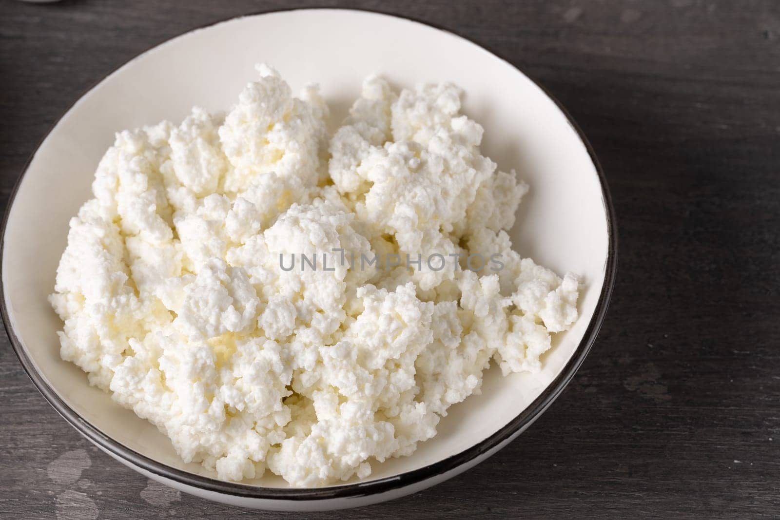 Bowl of cottage cheese isolated on grey background, top view.