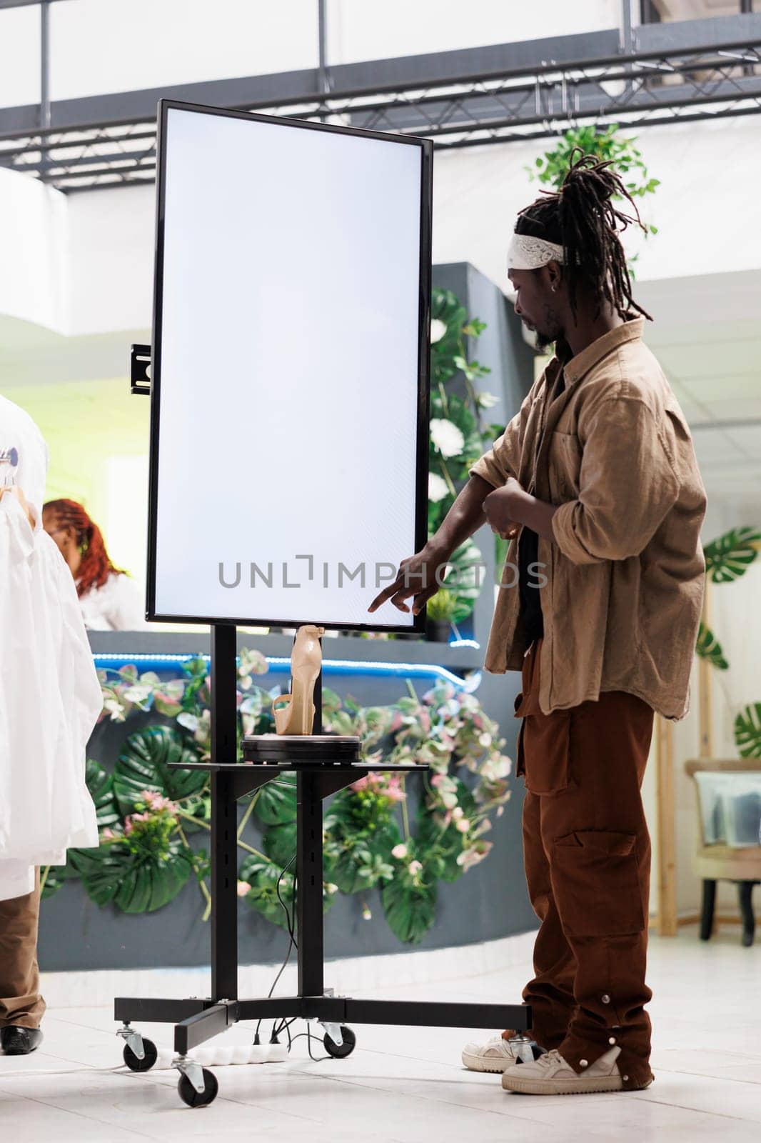 African american customer checking shoes advertisement on smart display board in boutique. Clothing store client reading information on whiteboard showcasing female stiletto brand collection