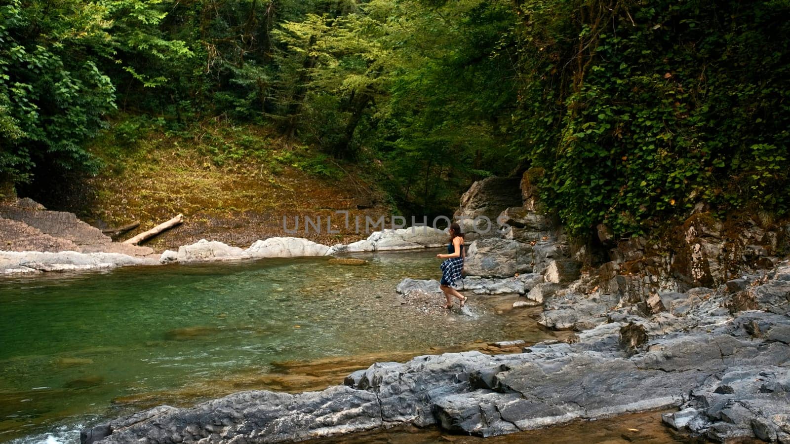 Woman hiker running in river on beautiful summer day. Creative. Paradise water reservoir in jungles