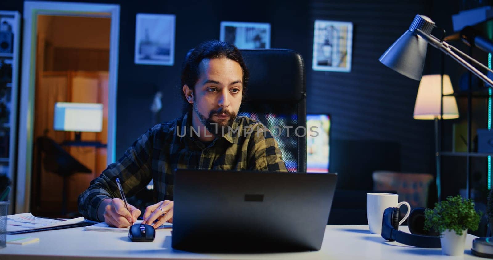 Freelancer noting down ideas on paper using pen while teleworking by DCStudio