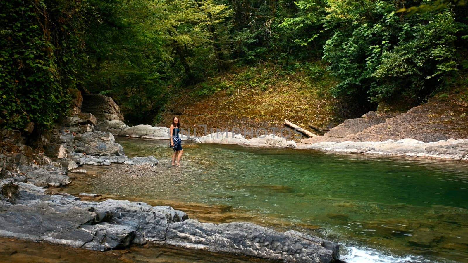 Man walking on the rocky river in paradise place. Creative. Woman cooling her feet in cld mountain stream